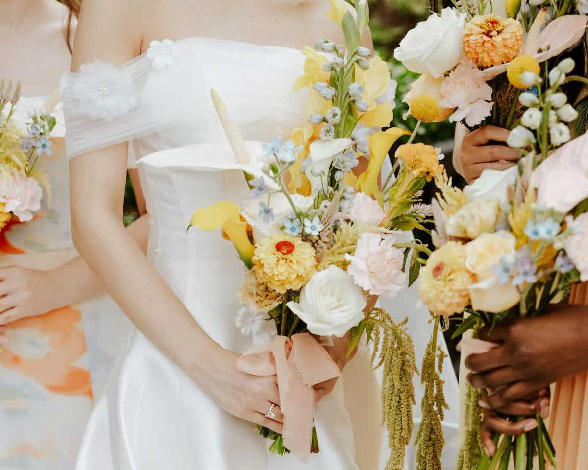 A close-up colorful bridal bouquet with yellow, white, and peach flowers made by Her Bloom Story